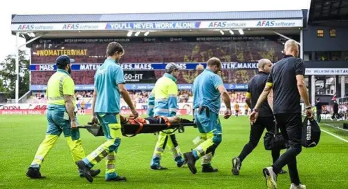 Event medics carrying a casualty on a stretcher across the pitch of a packed stadium
