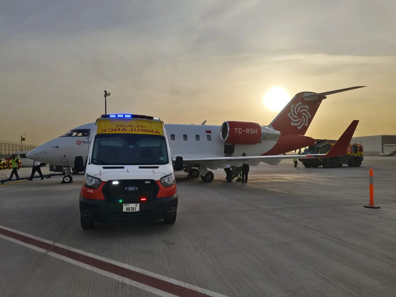 An ART ambulance parked on an airport apron alongside an air ambulance jet at sunset