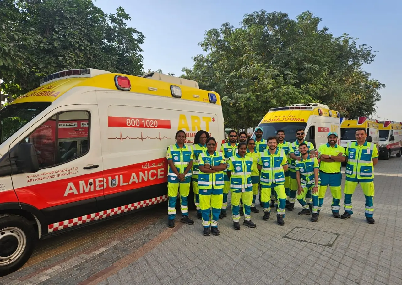 The ART Ambulance crew in high-visibility uniforms standing in front of a line of ART ambulances in Dubai